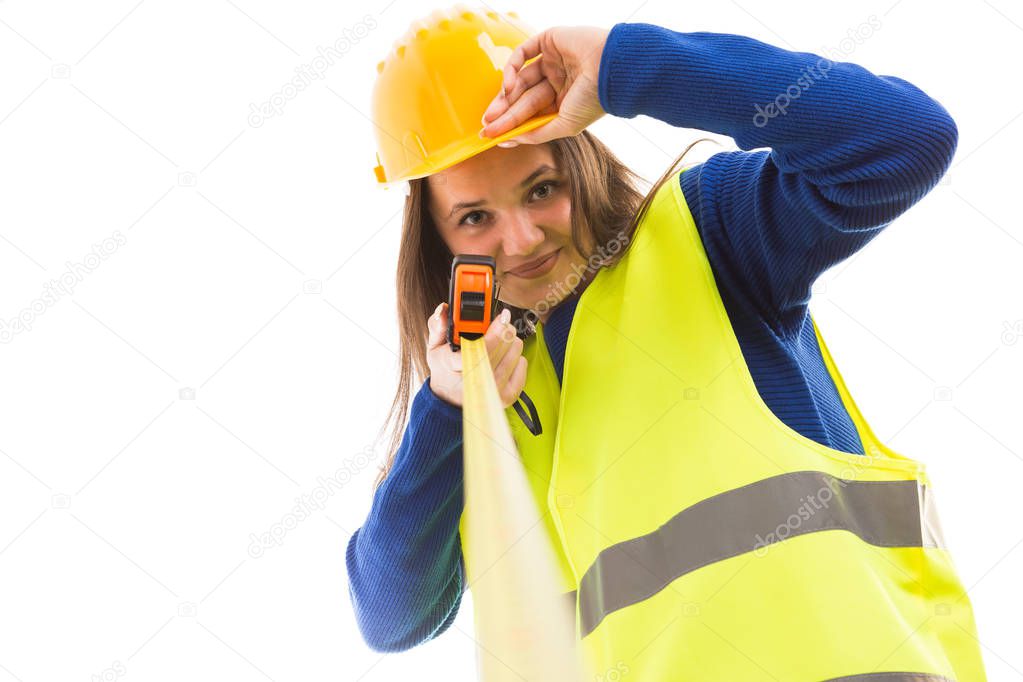 Young attractive female architect or engineer holding measuring tape and touching helmet as happy builder concept isolated on white background