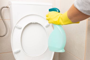 Beyaz klozet ve rezervuar sarı sıhhi giyen püskürtme kişi olarak temizlik kavramı eldiven
