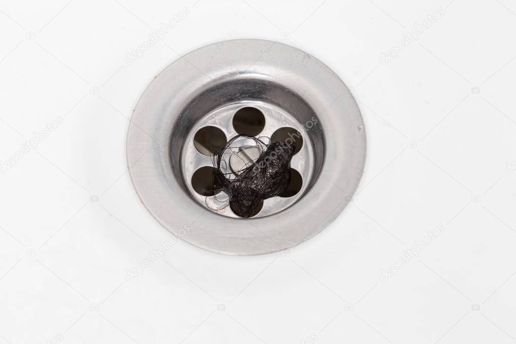 Strands of dark hair clogging drain made out of steel