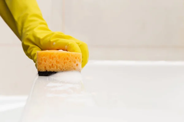 戴黄色卫生手套的人用海绵和泡沫清洗白色瓷水槽的边缘 — 图库照片