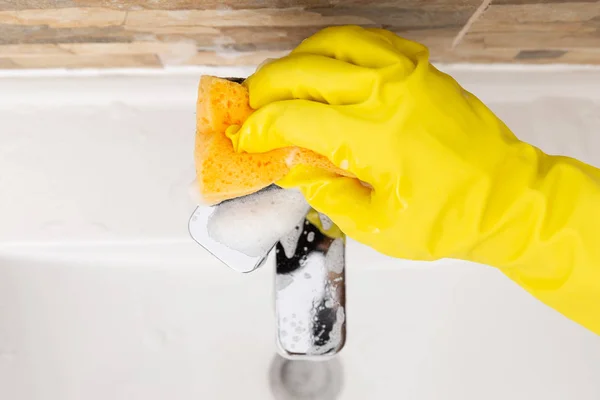 上面的形象人清洗水龙头用橙色海绵戴黄色橡胶手套作为家务的概念 — 图库照片