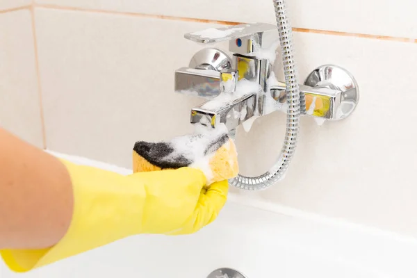 橙色海绵被用来清洁灰色水龙头从淋浴的人戴黄色手套作为卫生概念 — 图库照片