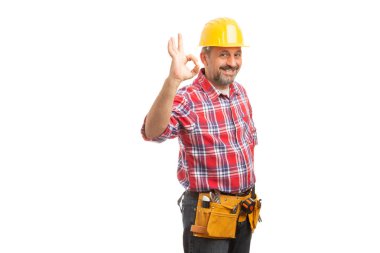 Beyaz arka plan üzerinde izole parmakları Tamam jest gösterilen sarı kask giyiyor neşeli erkek Oluşturucu