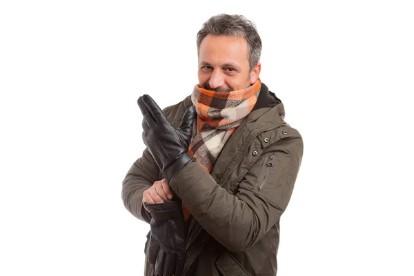 Kış ceket ve turuncu atkı eldiven soğuk hava beyaz stüdyo arka plan üzerinde izole için hazırlık olarak alarak giyen adam