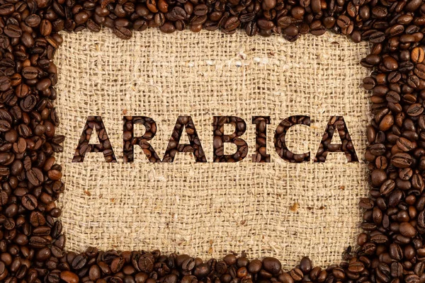 Arabica Escrito Con Granos Café Tostados Sobre Tela Fondo Texturizado —  Fotos de Stock