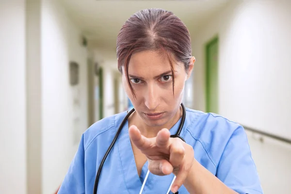 카메라 색인과 배경에서 당신을 보고으로 가운데 손가락으로 가리키는 간호사의 클로즈업 — 스톡 사진