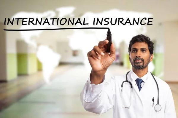 Male indian doctor underlining with black marker international insurance text on transparent screen having white world map background