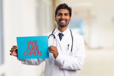 Erkek Hint Doktor ya da biz samimi ifade ile mavi kağıt üzerinde açık işareti metin tutuyorsun doktor