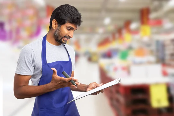 Supermarket employee looking at clipboar — Stock Photo, Image