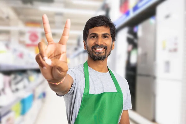 Supermarket employee showing victory gestur — Stock Photo, Image