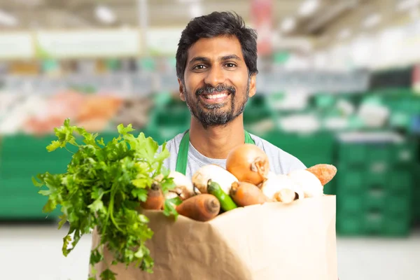 Grocery store employee holding bag of vegetable