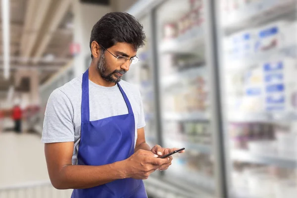 Supermarket employee texting on phon