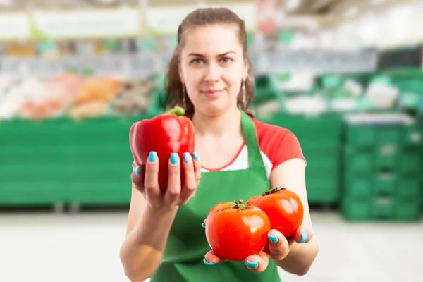 Grocery store employee presenting red, tomatoe — Stock Photo, Image
