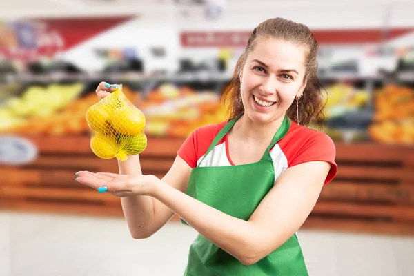 Grocery store employee presenting bag of lemon — Stock Photo, Image