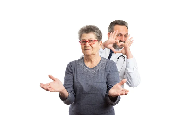 Médico haciendo el gesto del corazón detrás del paciente — Foto de Stock