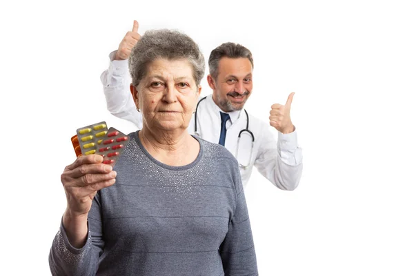 Paciente segurando remédio e médico segurando polegares para trás — Fotografia de Stock
