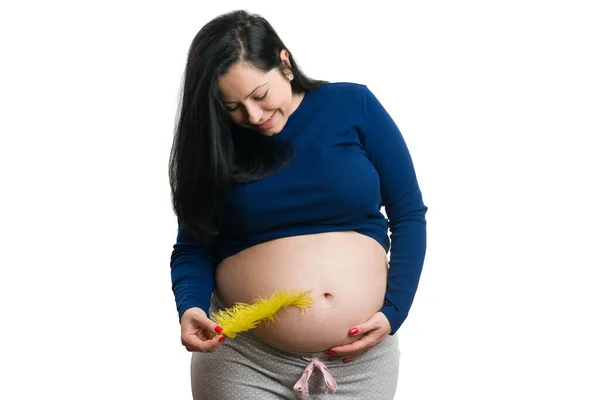 幸せな未来の母親は彼女のおなかに触れます黄色の羽と幸福の概念として白い背景に隔離 — ストック写真