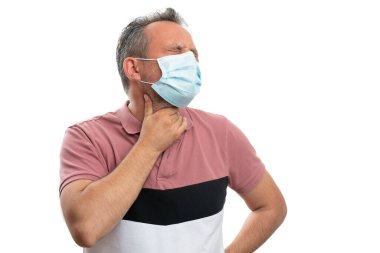 Boğazı ağrıyan, boğazı ağrıyan yetişkin bir adam. Grip salgını konsepti olarak beyaz stüdyo arka planında 19 numaralı kovidonun izole edilmesini önlemek için ameliyat maskesi takıyor.