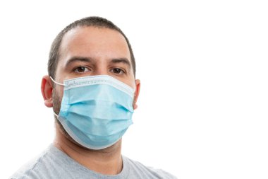 Tek kullanımlık tıbbi ya da cerrahi maske takan beyaz bir adamın yakın plan portresi. Stüdyo arka planında izole edilmiş reklamlar için boş telif alanı ile kovid19 enfeksiyon önleme kavramı.