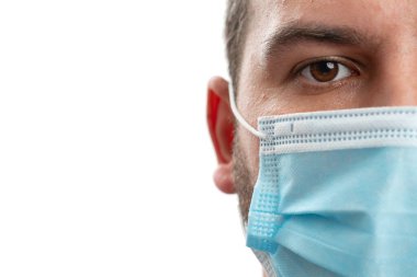 Tek kullanımlık tıbbi ya da cerrahi maske takan yetişkin erkek yüzüne yakın çekim. Beyaz stüdyo arka planında izole edilmiş mesajlar için boş telif alanı olan kovid19 grip salgınını önlemek için.