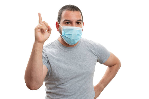 White adult man wearing surgical or medical disposable mask to prevent sars covid flu pandemic contamination making idea gesture with index finger isolated on studio background