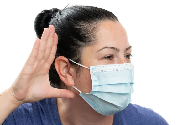 耳の手術や医療保護マスクを身に着けている耳に手で好奇心に耳を傾けるジェスチャーを作る大人の女性は 白に隔離されたコロナウイルスインフルエンザパンデミック — ストック写真