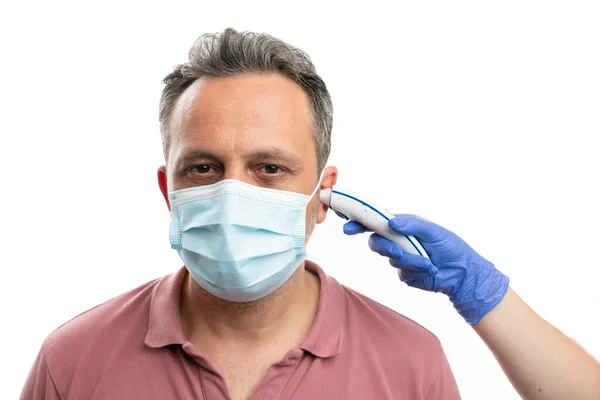 Mężczyzna Noszący Maskę Chirurgiczną Temperaturze Mierzonej Uchu Pomocą Termometru Laserowego — Zdjęcie stockowe
