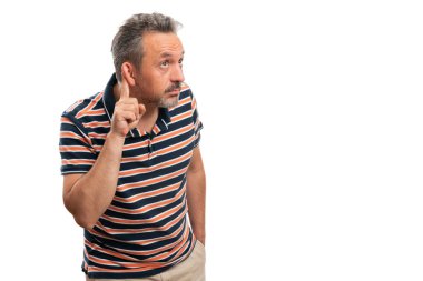 Meraklı yetişkin erkek modeli, reklam metinleri için boş telif alanı olan işaret parmağı kullanarak beyaz üzerine izole edilmiş yaz çizgili tişört giyerek dinleme hareketi yapıyor.