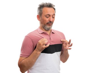 Gündelik modern kıyafetli bir adam renkli bir tişörtün pembe bir parçasını tutuyor ve beyaz arka planda izole edilmiş reklamlar için boş telif alanı ile tiksindirici bir ifade oluşturuyor.