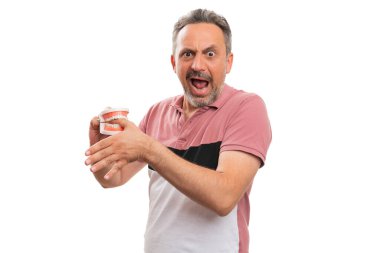 Takma diş protezi. Yetişkin erkek modelin başparmağını ısırıyor. Yaralı yüz ifadesi yapıyor.