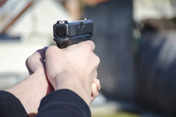 A gun in the hands of a man ready for a shot with blurred backfround.