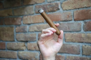 El puro ile bulanık duvar arka planda yanan tutar.