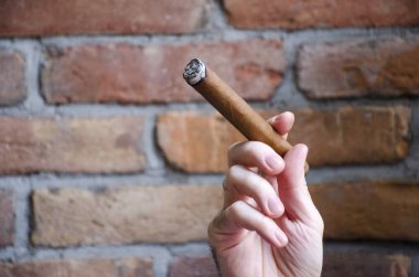 El puro ile bulanık duvar arka planda yanan tutar.