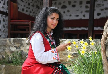 Güzel genç kadın bir bahçede poz bir Bulgar geleneksel folklor kostüm giymiş
