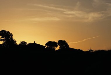 Bir haç ve çatı ile şehir tepelerin üstünde altın bir gün batımı