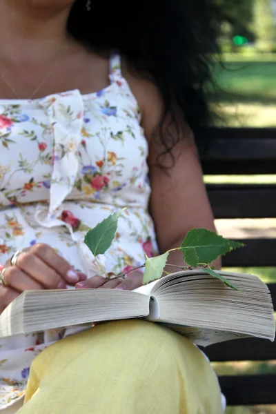 一个年轻漂亮的长着卷发的女人正在公园里看书 — 图库照片