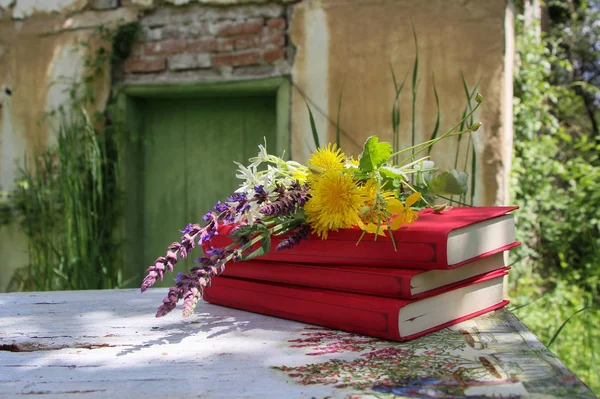 Still life in a rural garden with books and wild flowers on a vintage table
