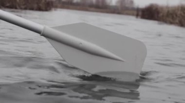 Tekne nehirde yüzüyor, kürek suya indirilmiş.