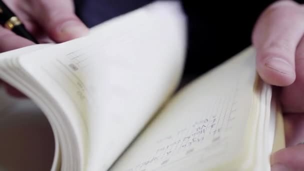 Écrit un stylo dans son journal, à la recherche d'entrées dans un carnet .