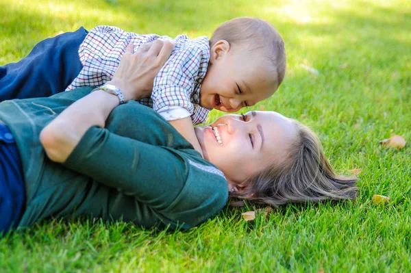 幸せママと息子が公園の芝生の上に横たわっています — ストック写真