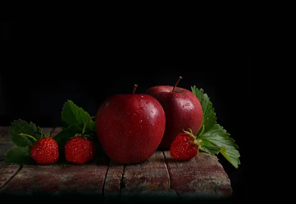 Red apples and strawberries on a dark background. Still life of fruit and berries.