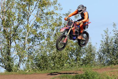 Mavi gökyüzü ve yeşil ağaçlar karşı uçan motosiklet yarışçısı. Aşırı aktif dinlenme.