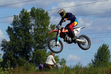 Kiev, Ukrayna - Ağustos 22, 2018. Mavi bir gökyüzü ve yeşil ağaçlar arka planı, bir toprak yol bir bisikletçi sürmek ve bir motosiklet yarışçısı onu uçar. Aşırı aktif dinlenme.