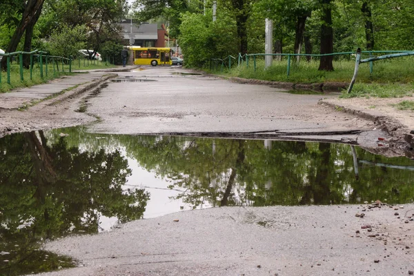 Very large, deep pit with water for the entire width of the road after the sewer repair. People bypass the pit on the sidelines. Risk of driving a car.