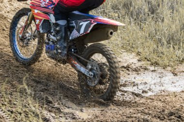 Motocross. Motosikletçi toprak bir yol boyunca koşar, toprak tekerleklerin altından uçar. Aktif aşırı dinlenme.