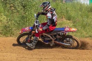 Motocross. Motosikletçi toprak bir yolda koşar, tekerleklerin altından toz uçar. Close. Aktif aşırı dinlenme.