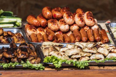 Etli, sosisli ve ızgara sebzeli çeşitli sağlıklı yiyecekler sunan bir açık büfe. Açık havada mutfak..
