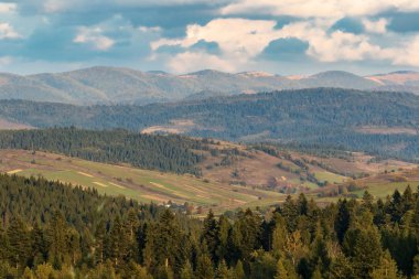 Yüksek dağlar ve mavi bulutlu gökyüzü. Birkaç küçük ev. Sonbahar manzarası. Panoramik görünüm.