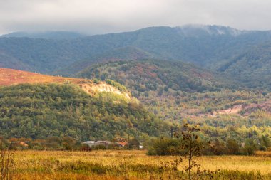 Yüksek dağlar ve mavi bulutlu gökyüzü. Birkaç küçük ev. Sonbahar manzarası. Panoramik görünüm.