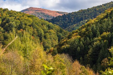 Yüksek dağlar ve mavi bulutlu gökyüzü. Birkaç küçük ev. Sonbahar manzarası. Panoramik görünüm.